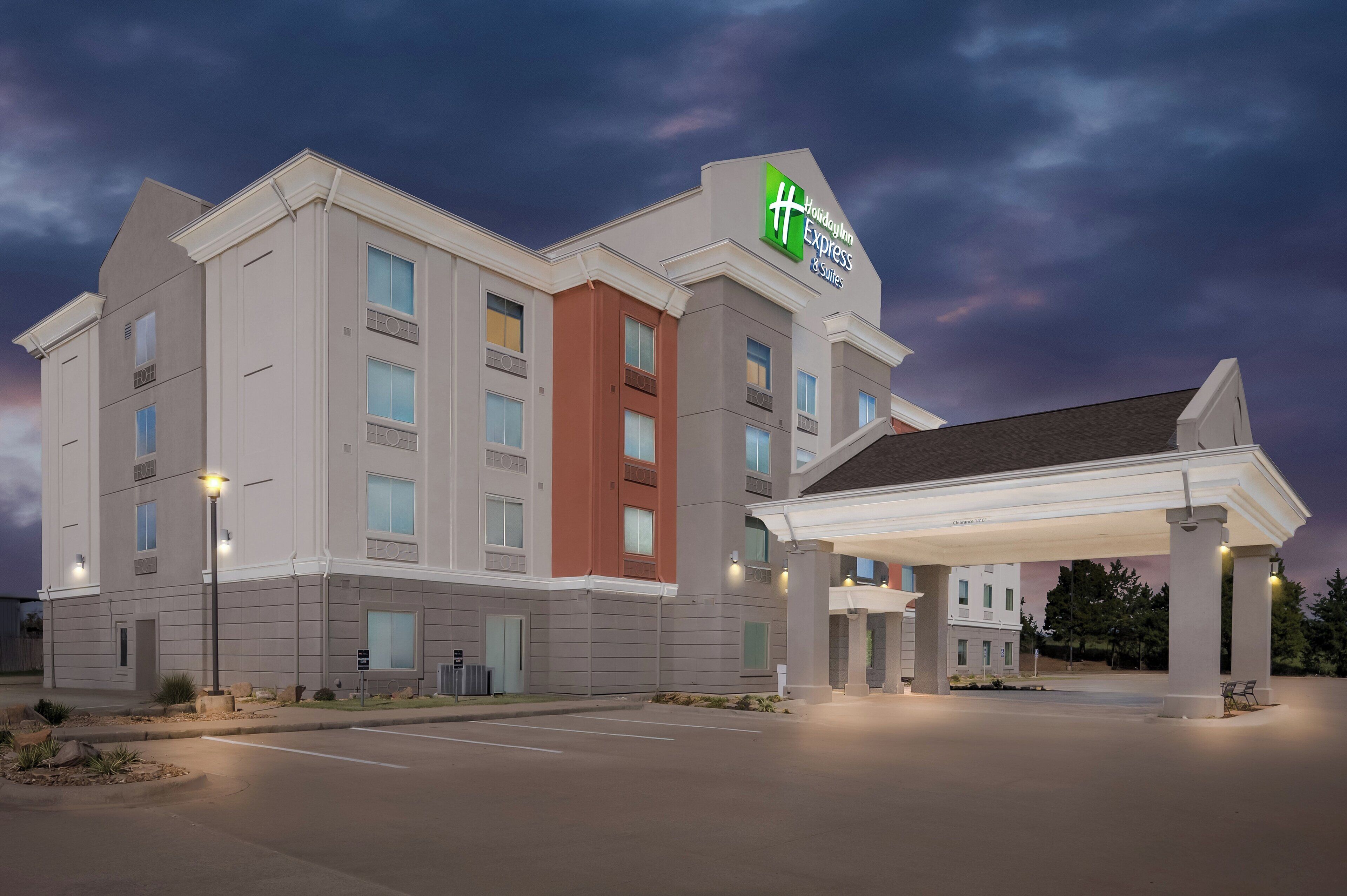 Ein Holiday Inn Express & Suites Hotel mit modernem Design, das einen überdachten Parkbereich und einen gut beleuchteten Eingang bietet.