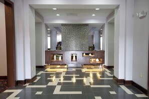 A hotel reception area with a check-in counter, a decorative mosaic wall, and a patterned floor.