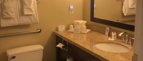A hotel bathroom with a toilet, sink, and towel rack.