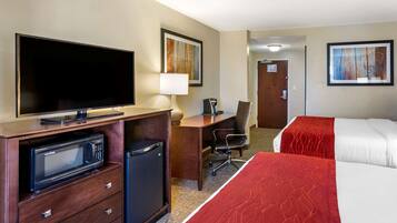 A hotel room with a bed, a desk, a television, a microwave, and a refrigerator.