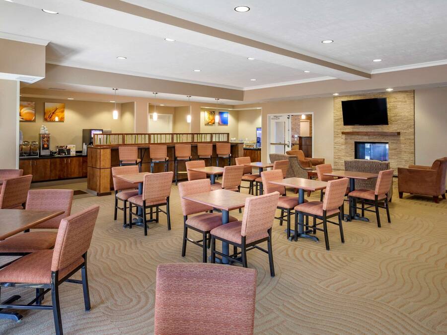A spacious hotel lobby with multiple seating areas, a reception desk, and a television mounted on the wall.