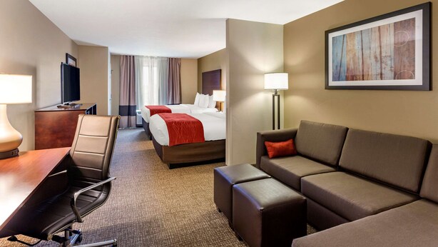 A hotel room with a desk, two beds, a sofa, and a painting on the wall. - Comfort Inn & Suites Tooele - Salt Lake City (Tooele)