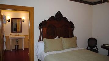 Une chambre à coucher avec un lit en bois, une table de chevet blanche, une chaise et un petit bureau avec une lampe.