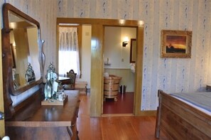 Una habitación con una cama de madera, un espejo grande, un aparador de madera y un cuadro en la pared.