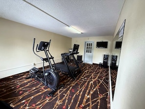 A hotel room with a treadmill, elliptical, and stationary bike.