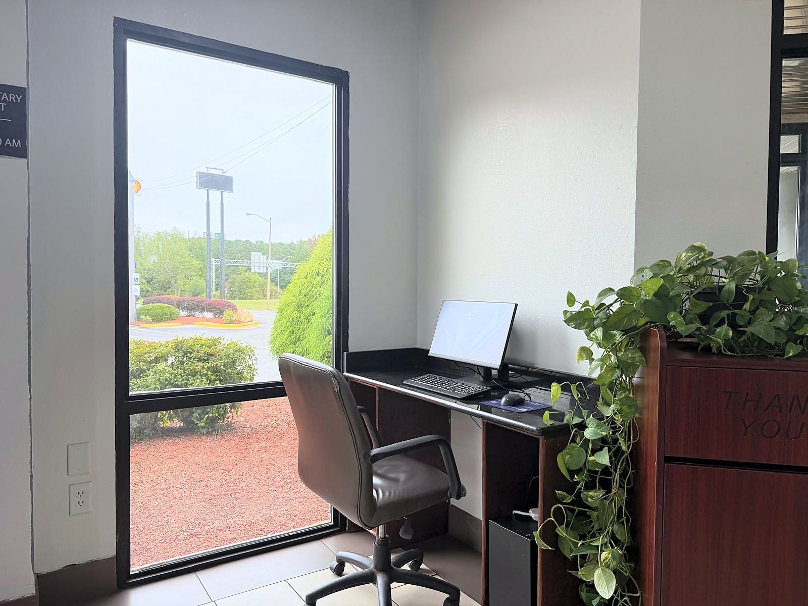 A corner office with a desk, chair, laptop, and a potted plant.