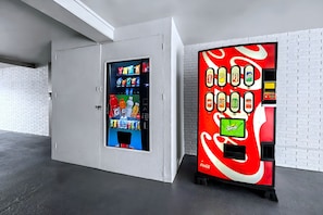 Two vending machines in a room with white brick walls and a concrete floor.