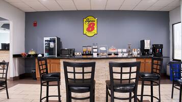 Una cafetería Super 8 con barra, mesas y una máquina de café.