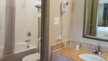 A bathroom with a bathtub, toilet, and a sink with a mirror.