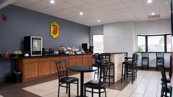 A restaurant with a counter, chairs, and a large window.