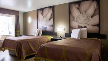 Habitación de hotel con dos camas, un escritorio, una silla, un teléfono y una obra de arte floral grande en la pared.