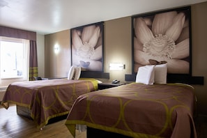 A hotel room with two beds, a desk, a chair, a telephone, and a large floral artwork on the wall. - Quality Inn (Garysburg)