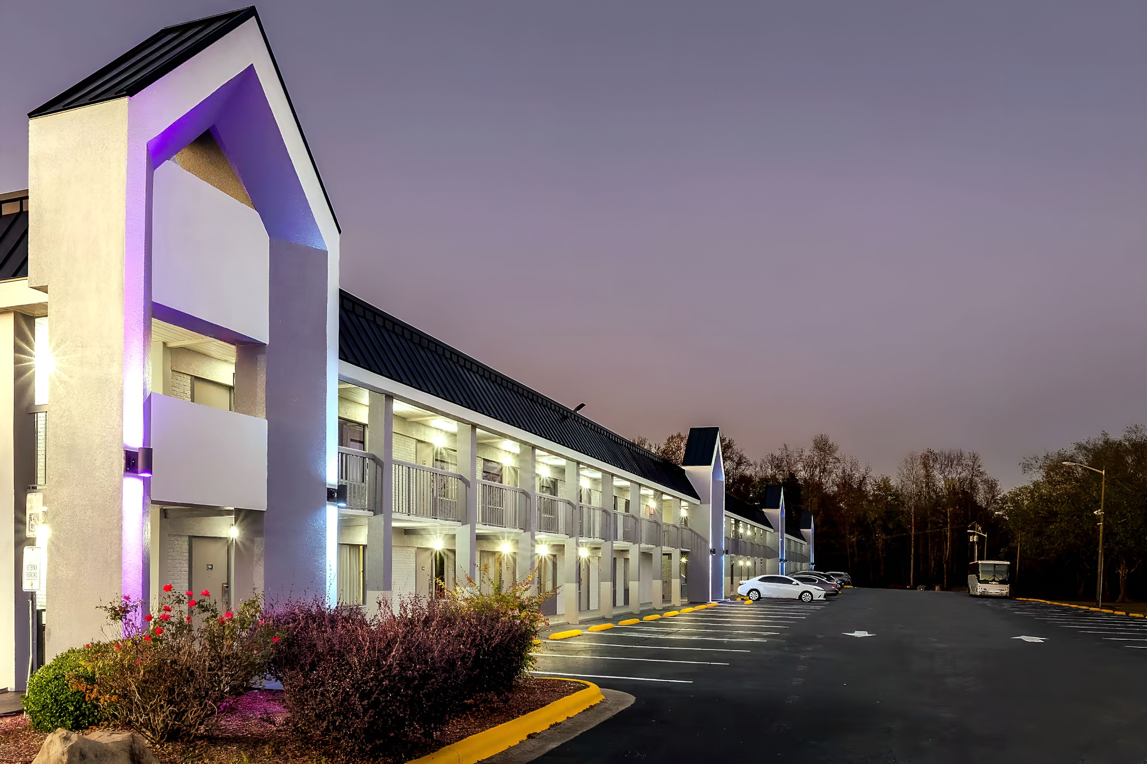 A multi-story hotel with a modern design, featuring a series of balconies and a parking lot.