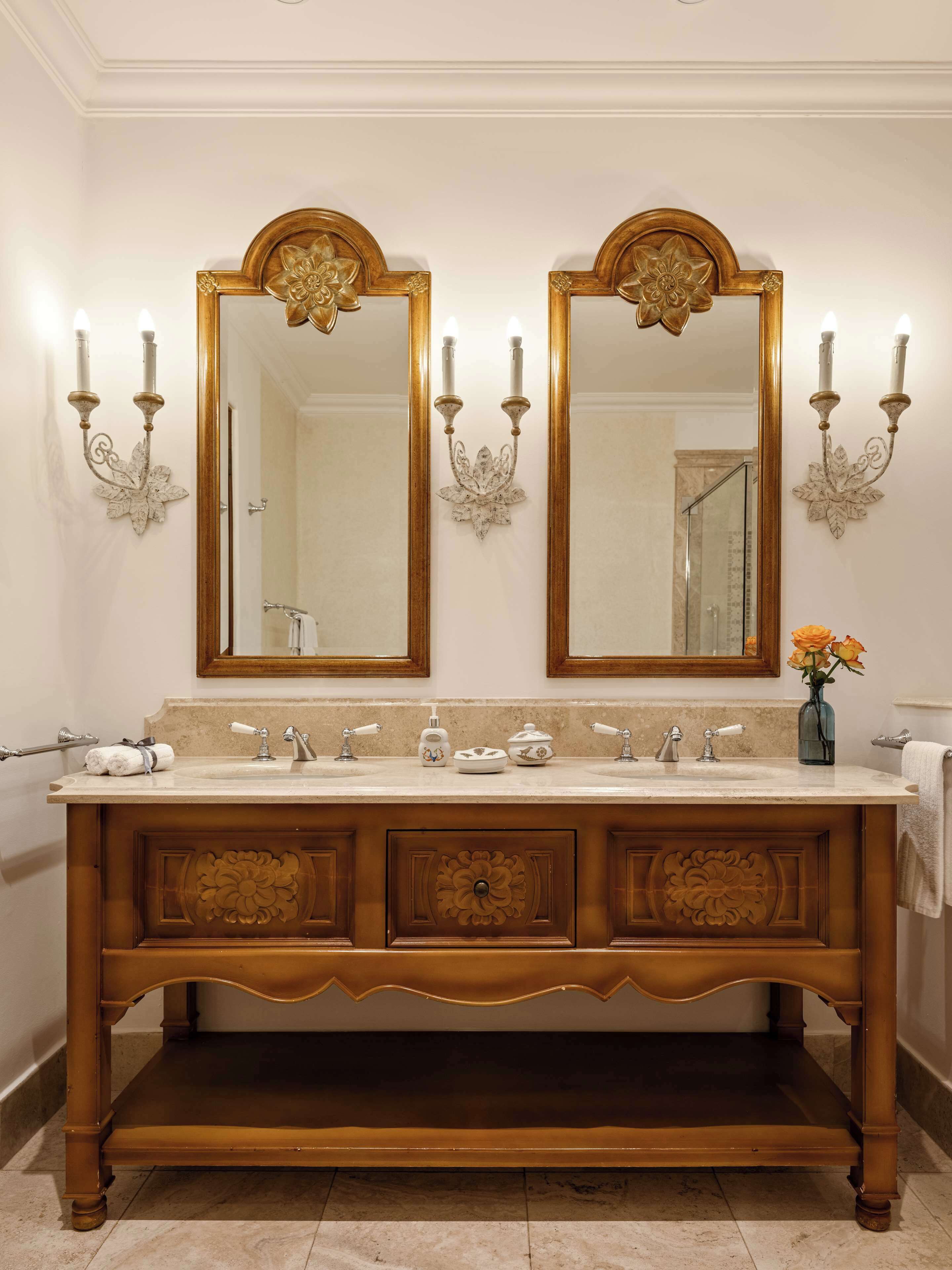 A bathroom with a double vanity, two wall-mounted mirrors, and a vase with flowers.