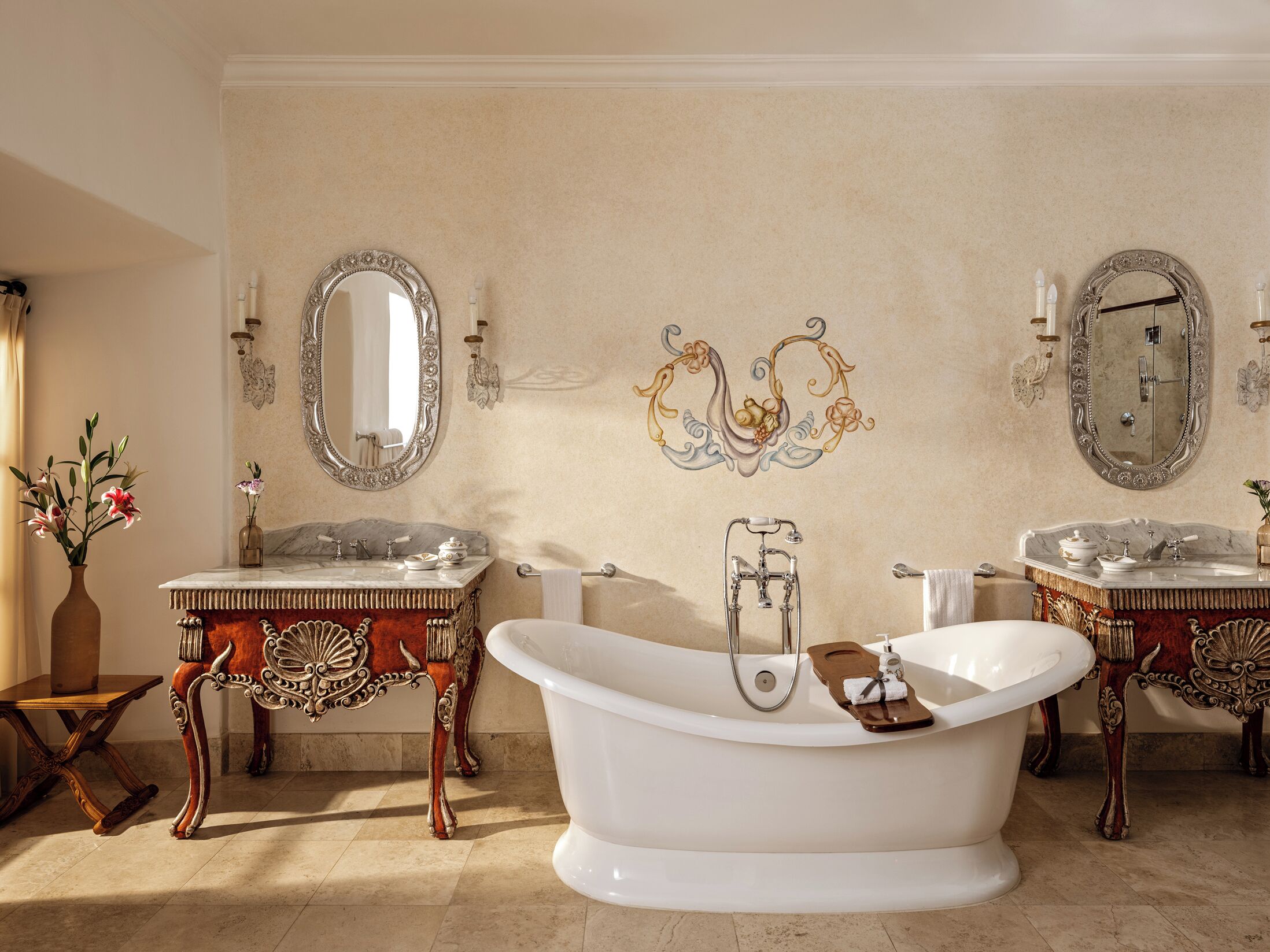 A classic bathroom with two sinks, a freestanding bathtub, and ornate wall decorations.