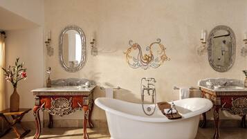 Un baño clásico con dos lavamanos, una bañera independiente y decoraciones de pared elaboradas.