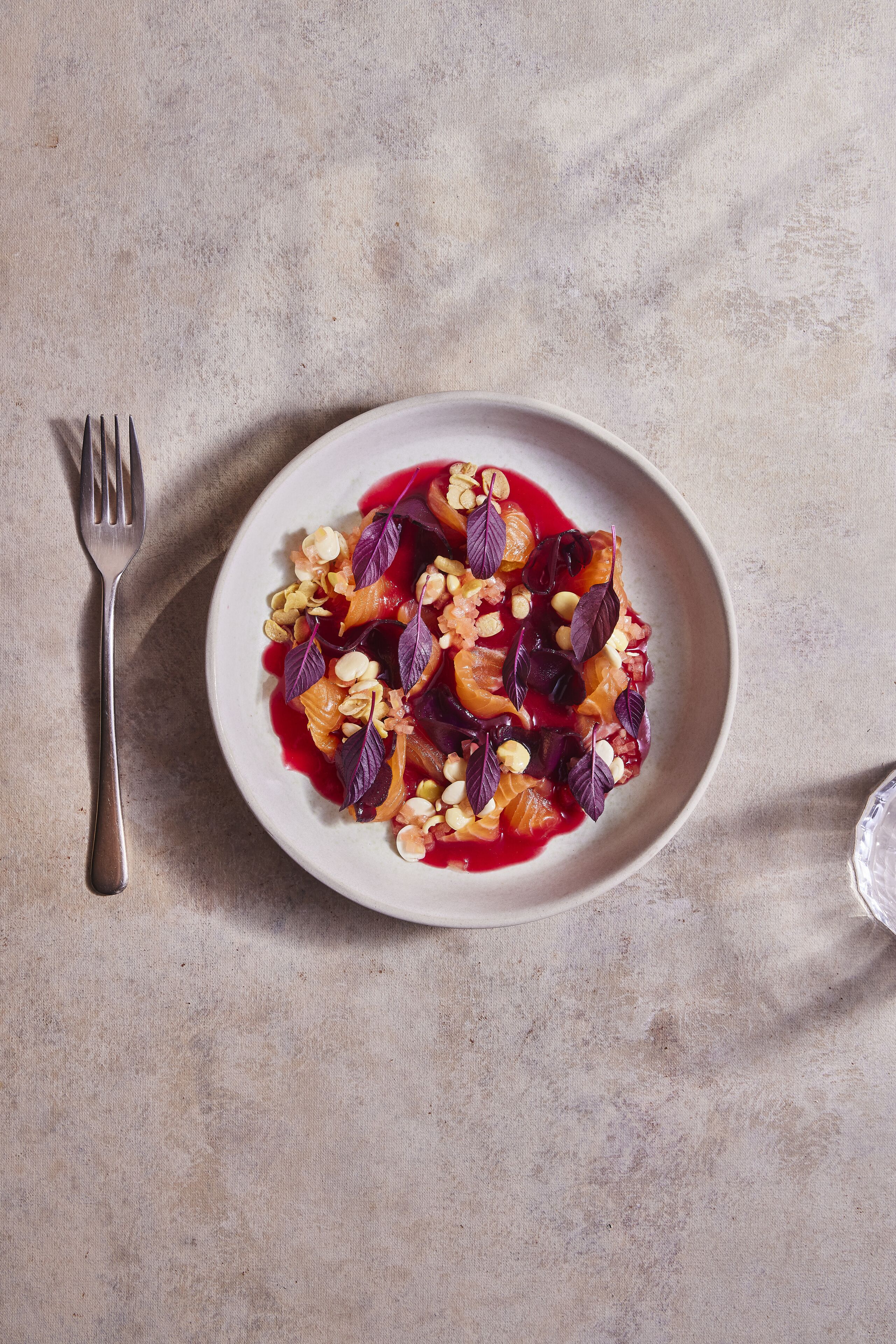 A plate of food with a fork beside it on a textured surface.