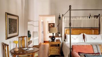 Un dormitorio con una cama con dosel, una mesita de noche de madera, una silla, una mesa y un cuadro en la pared.