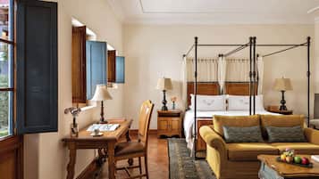 Una habitación con una cama con dosel, un sofá, una mesa con lámpara y una silla.