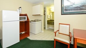 A compact kitchenette with a refrigerator, microwave, and sink. There is a small dining area with a chair and table. - Angus Inn (Essa)