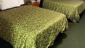 A hotel room with two beds, a nightstand, a lamp, and two framed pictures on the wall. - Angus Inn (Essa)
