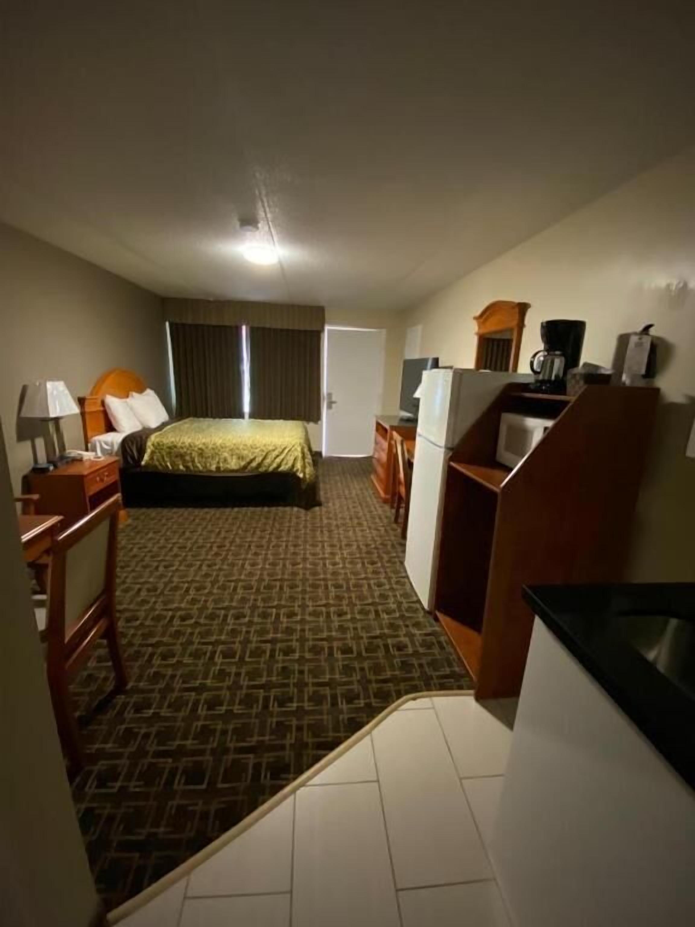 Een hotelkamer met een bed, een bureau, een stoel, een koelkast en een televisie.