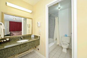 A bathroom with a granite countertop sink, a mirror, a shower, and a toilet.