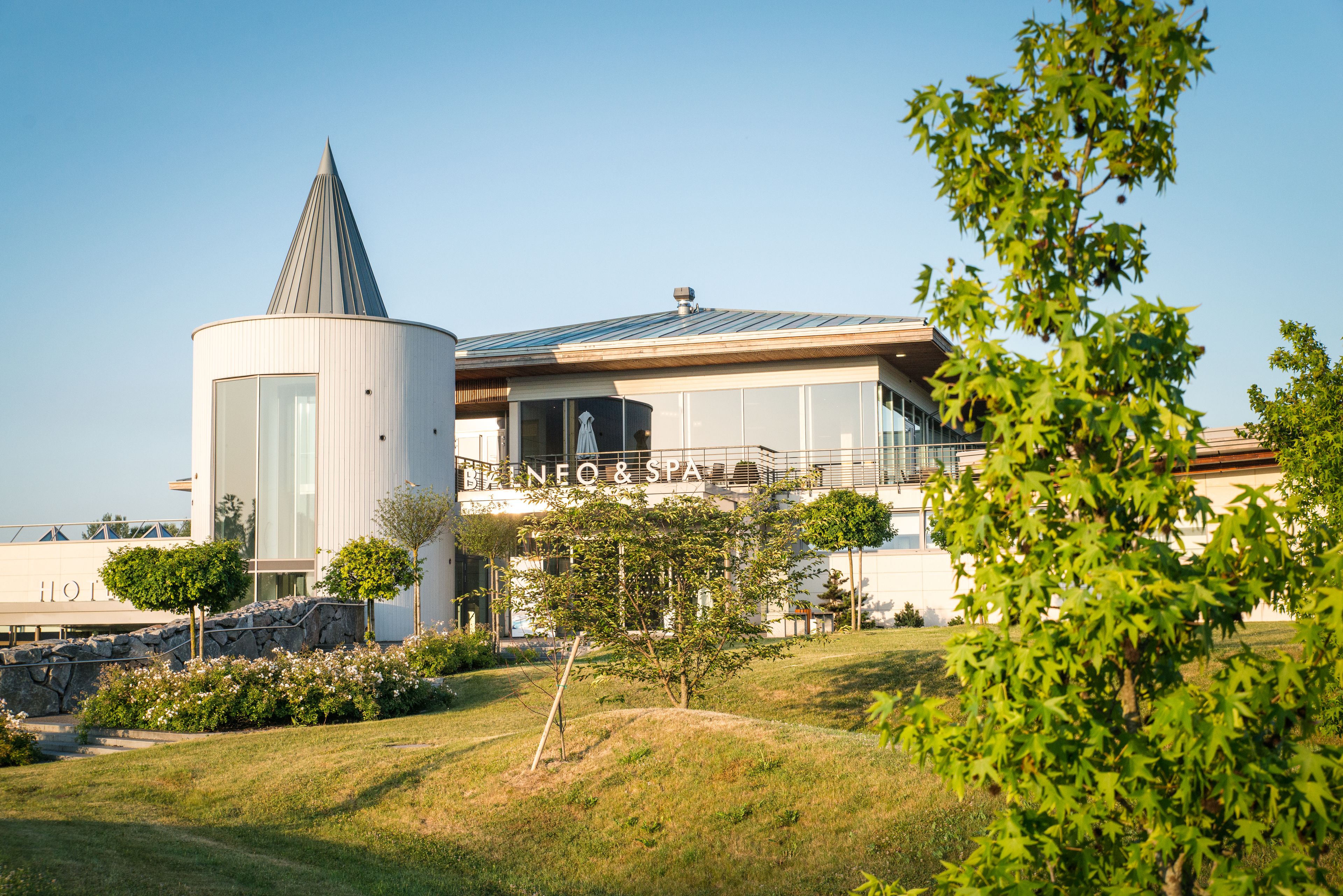 A modern hotel with a distinctive conical tower and a spa facility.