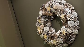 A wreath with pinecones and starfish on a dark wall, next to a door with a sign reading "312".