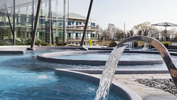 Una piscina con fuente, rodeada por un espacio cubierto con paredes de vidrio.