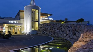 A hotel with a modern design, featuring a prominent cylindrical structure and a stone wall. - Resort Barrière Ribeauvillé (Ribeauvillé)