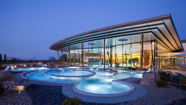 A modern building with a glass facade and a pool area with multiple hot tubs. - Resort Barrière Ribeauvillé (Ribeauvillé)