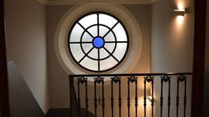 Una escalera con barandilla decorativa y un ventanal circular con centro azul.