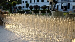 Una mesa con numerosas copas de vino vacías, una carpa arriba y un edificio al fondo.