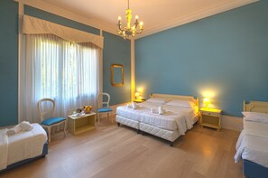 A hotel room with two beds, a chandelier, a chair, a small table with a lamp, and a window with curtains. - Villa Marcello Giustinian (Mogliano Veneto)