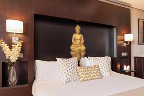 A hotel room with a large bed, a golden Buddha statue, white and gold patterned pillows, and wall-mounted lamps. - Oh Nice Ulises Ceuta (Ceuta)