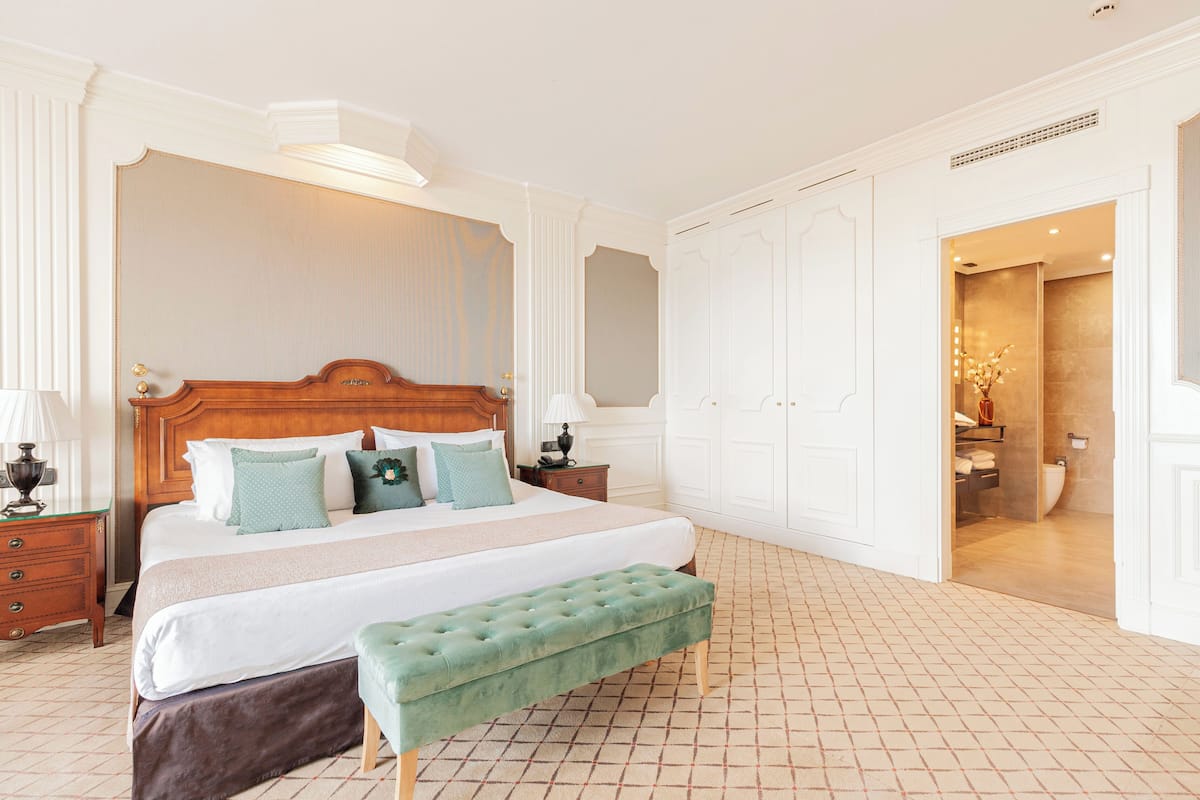 Une chambre spacieuse avec un grand lit, un banc et une armoire.