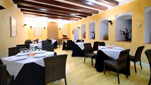 A restaurant with multiple tables set for dining, featuring dark wicker chairs and white tablecloths. - Hotel AHC Palacio Coria (Coria)