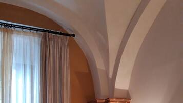 Habitación de hotel con cama, dos lámparas de noche, mesitas de noche, una lámpara y una ventana con cortinas.