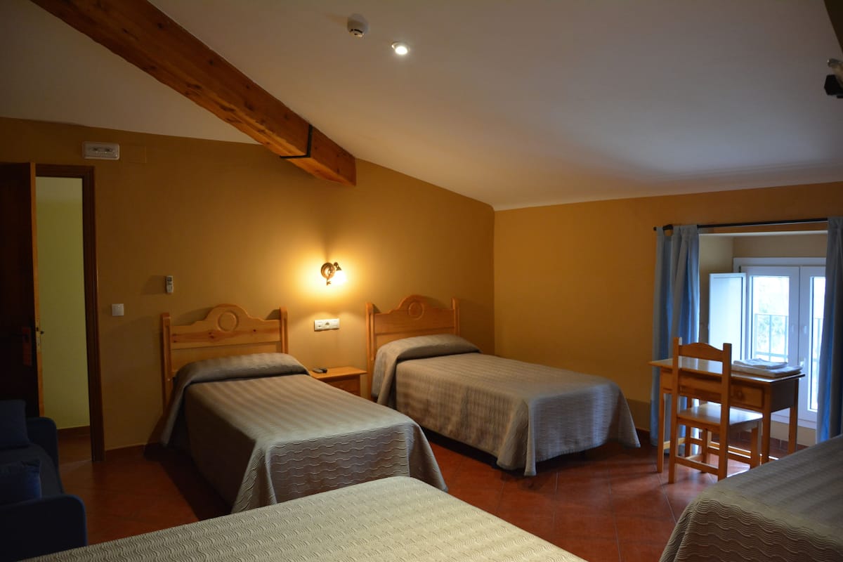 Una habitación con dos camas individuales, un escritorio de madera y una silla.
