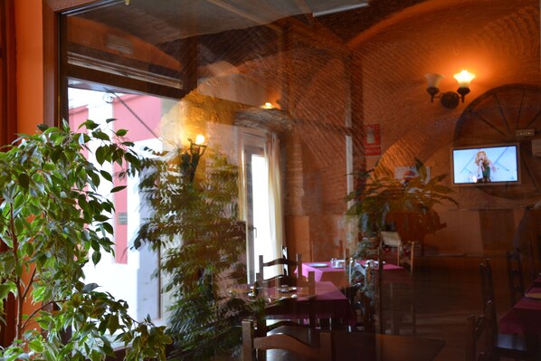 A restaurant with brick walls, a large window, and a television screen.