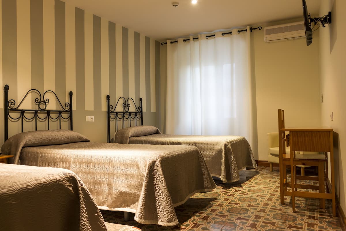 Habitación de hotel con dos camas, una silla y piso estampado.