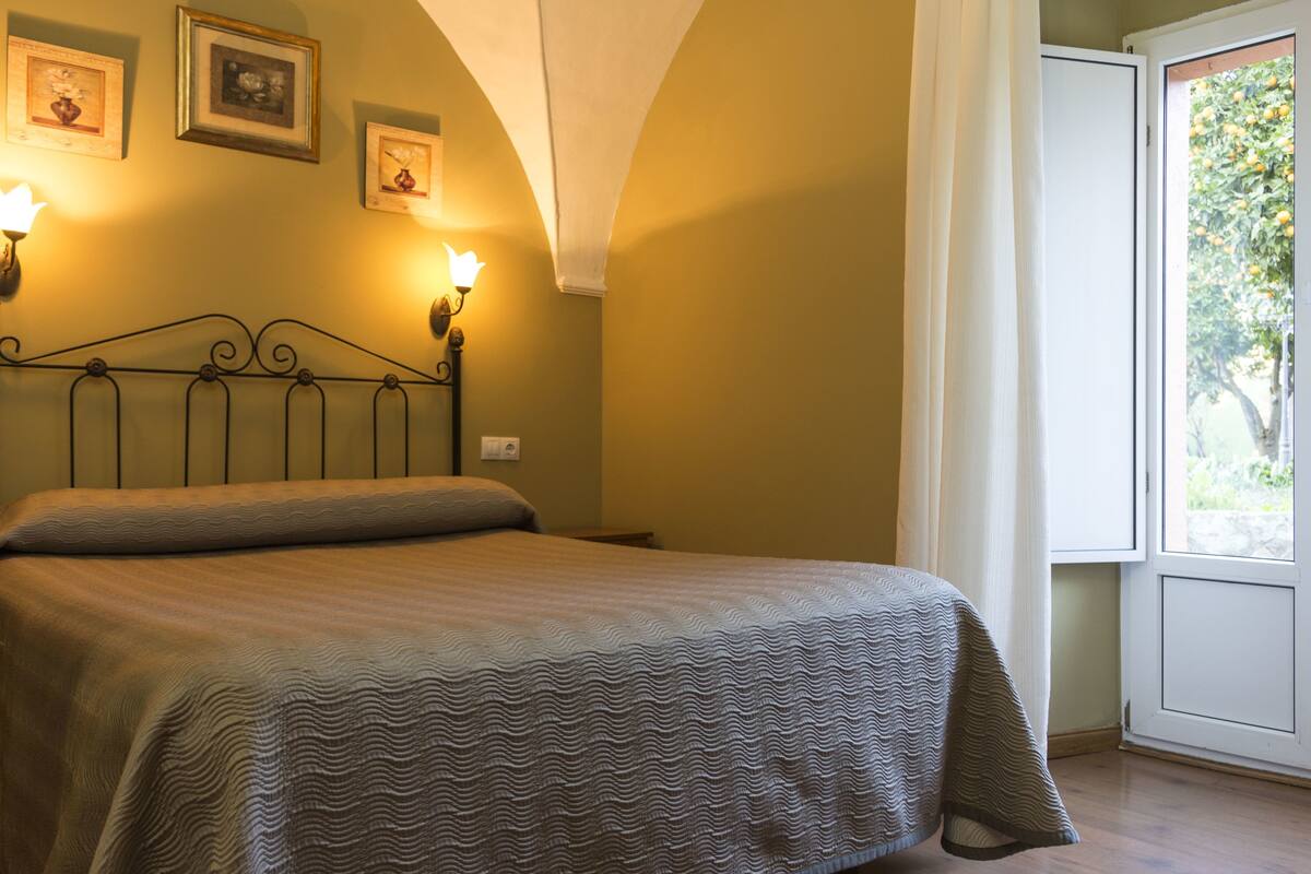 Un dormitorio con una cama, dos lámparas de pared y cuadros en la pared.