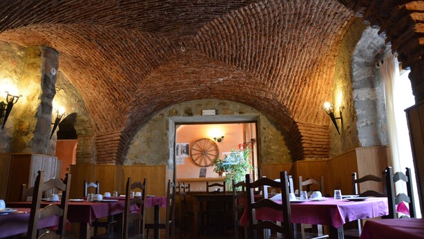 Un coin repas rustique avec des arches en briques, des tables et des chaises en bois.