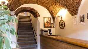 Un espace d’accueil avec un comptoir en bois, une horloge et un escalier menant à un niveau supérieur.
