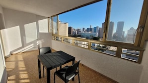Un balcon avec une table et des chaises, une vue sur la ville et un immeuble en arrière-plan.