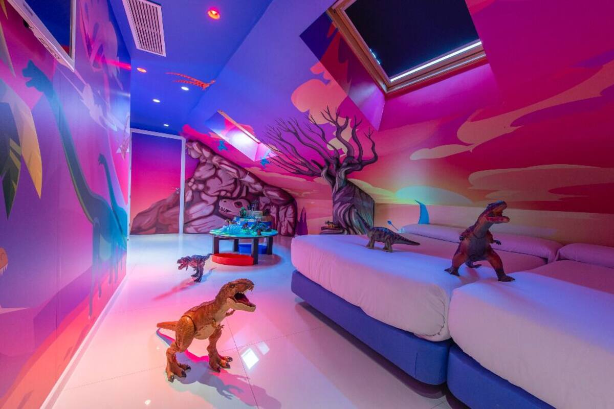 Una habitación decorada con temática de dinosaurios, que incluye un sofá y una mesa con figuras de dinosaurios.