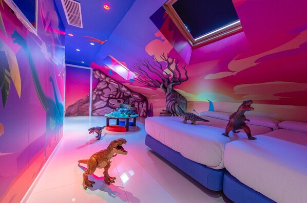 A room with dinosaur-themed decor, including a sofa and a table with dinosaur figurines.