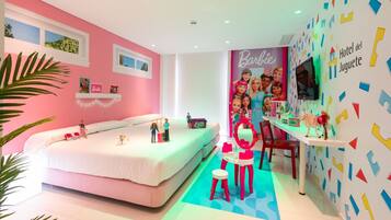 A pink-themed room with a bed, a small table, and a Barbie-themed wall.