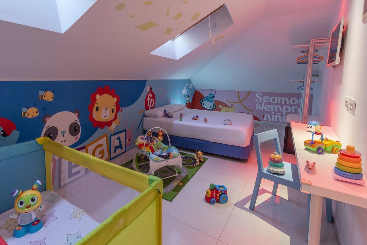 Un cuarto infantil con una cama litera, juguetes y un tragaluz en el techo.